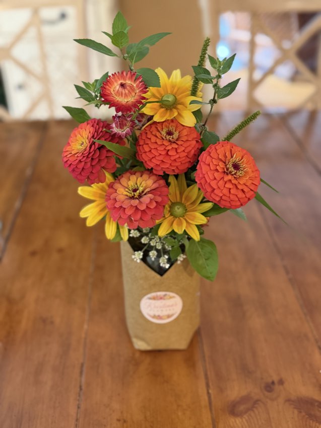 A bouquet of zinnias and sunflowers on a table