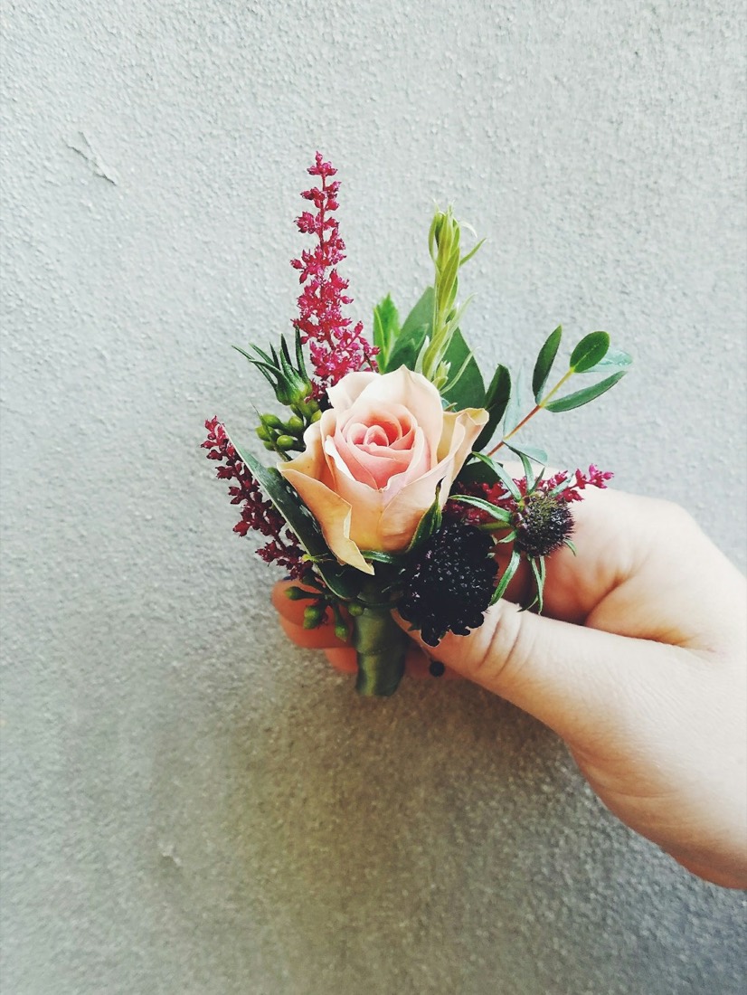 A hand holding a rose boutonniere