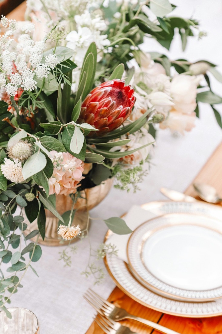 A dinner table with a protea centerpiece