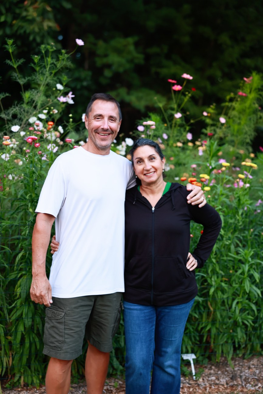 Two people smiling in front of the flower garden